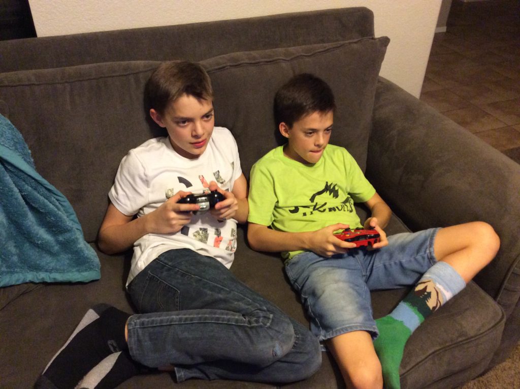 two boys playing video games on the couch