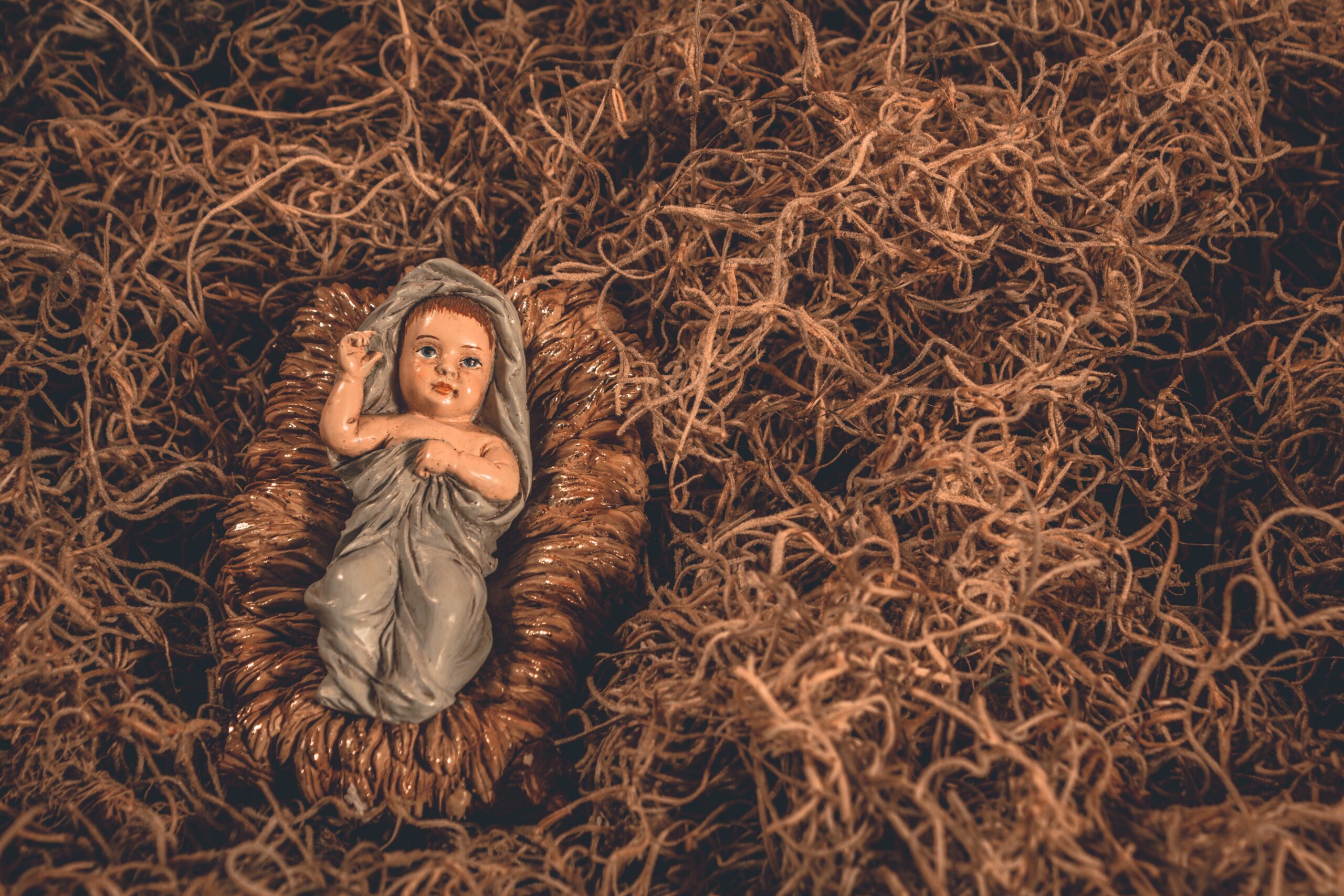 Baby Jesus figurine from a nativity set laying in straw