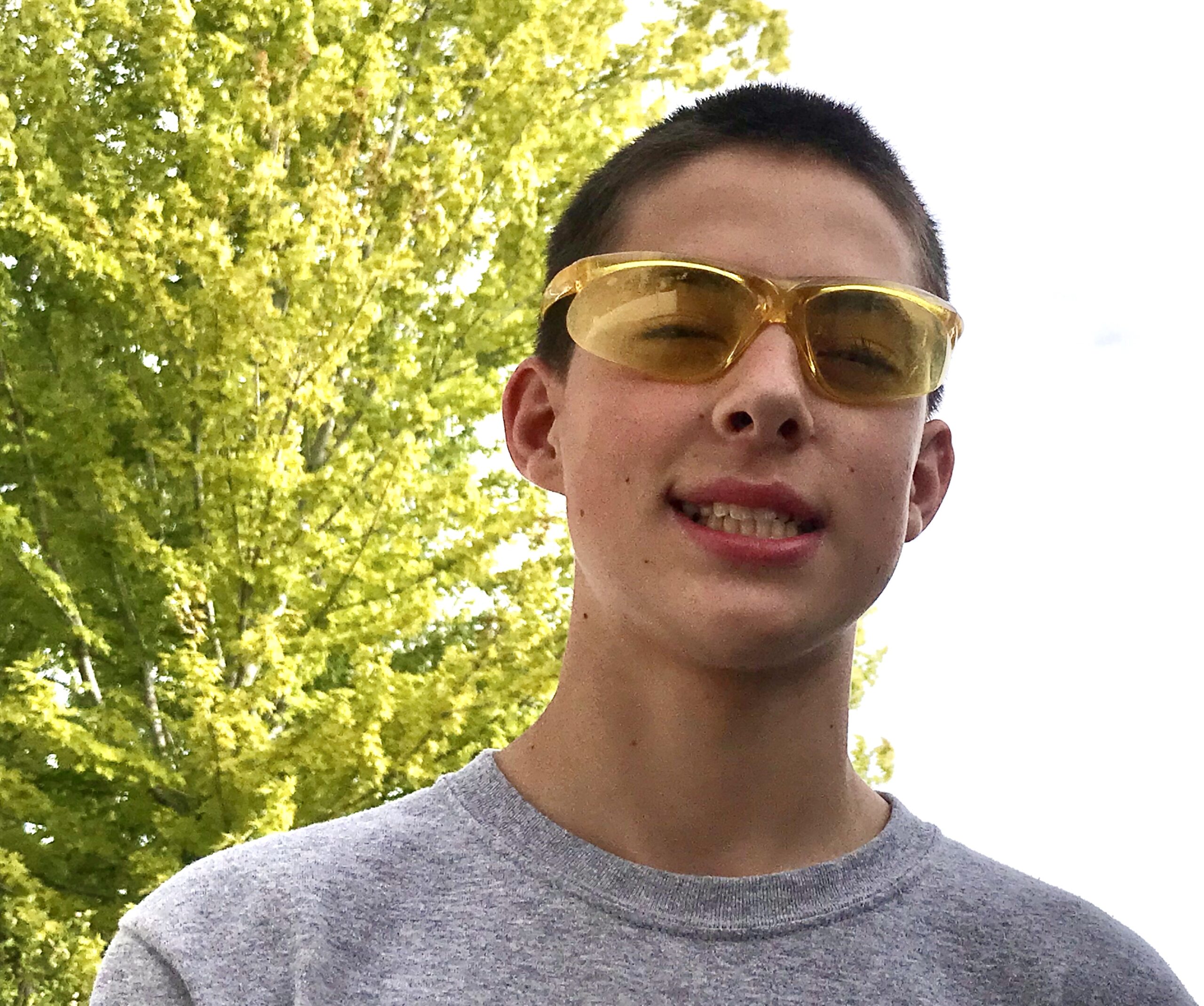 a teenage boy outside with science goggles on in front of a tree