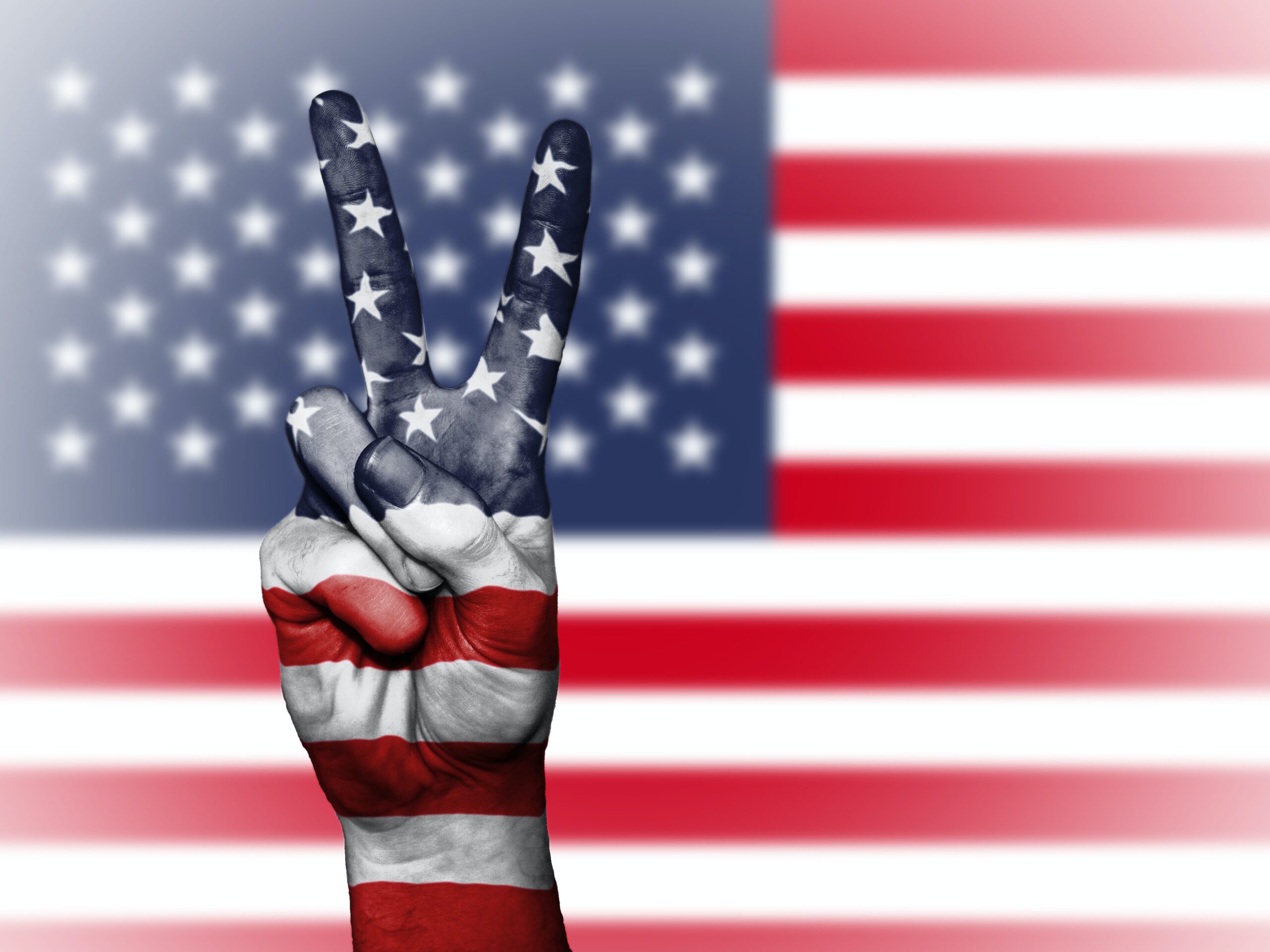 a person making the peace sign in front of an American flag