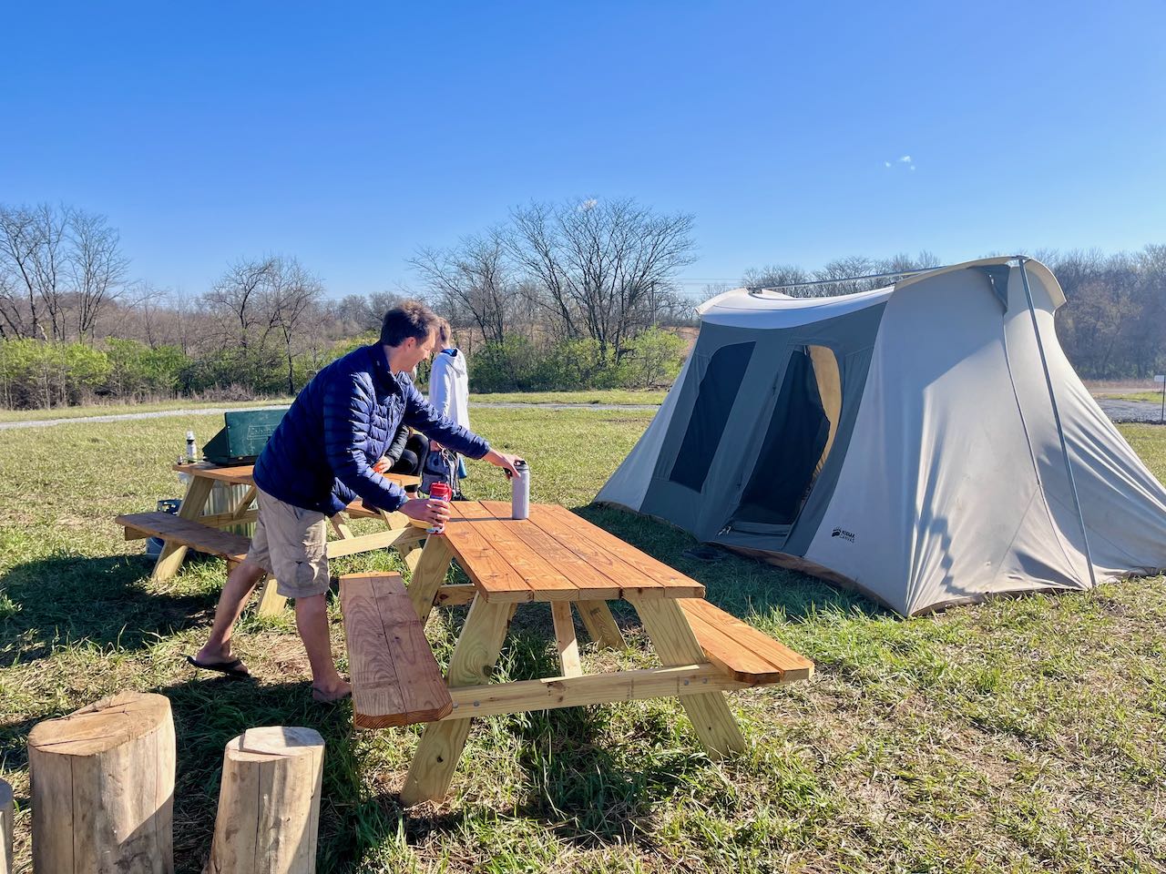 setting up camping site with tent, table, man and water bottle